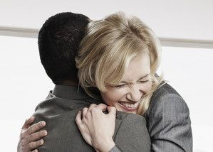 Two business people hugging in office